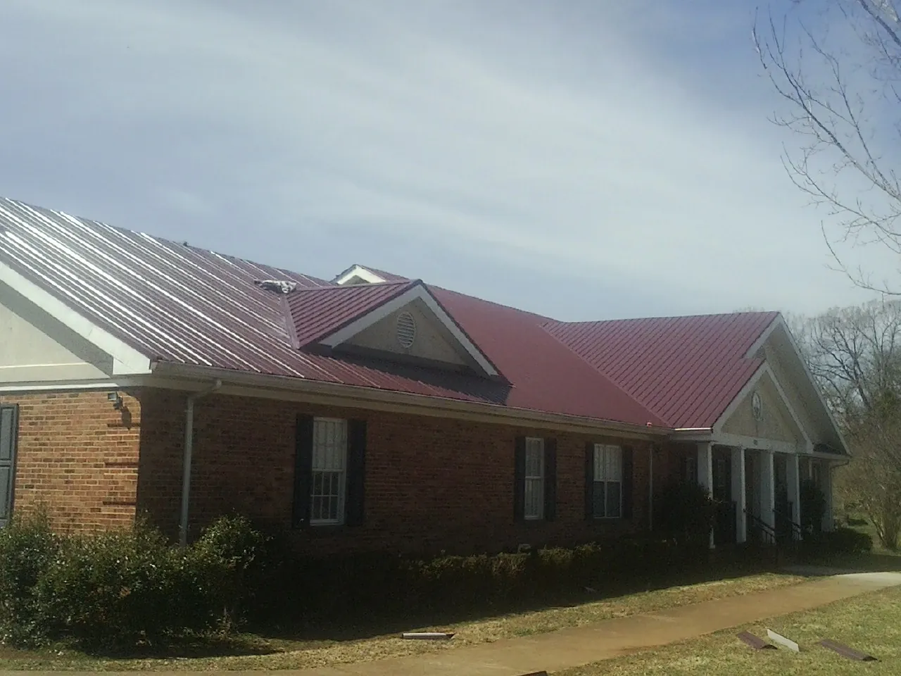 Red metal roof with gabled entries on a long brick building in Graham