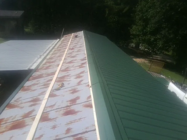Old rusted panels beside newly installed green metal roofing — Wind Damage Roof Repair by Roofing Brothers in Graham